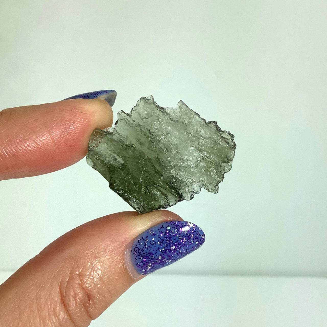 Person holding Moldavite raw glitter, 1.1’ Besednice rough from Czech Republic