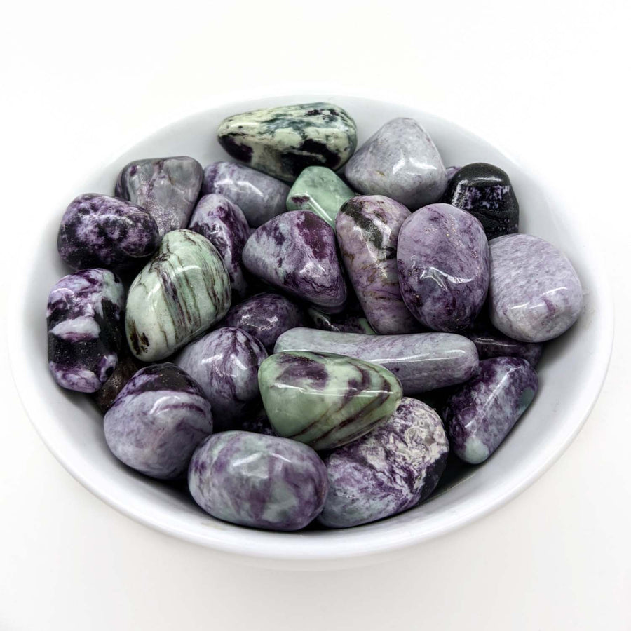 Polished purple and green fluorite stones in a bowl featuring Kammererite Tumbled Stone