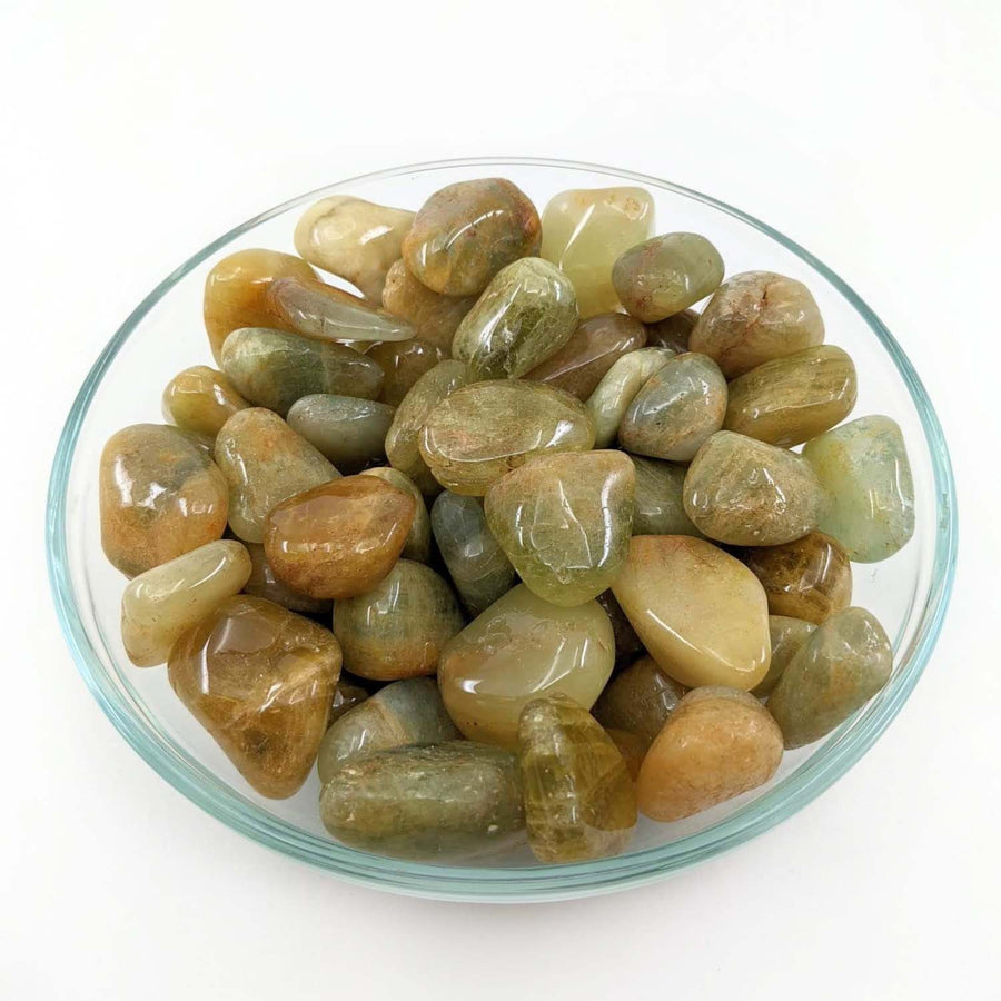 Polished Moonstone pebbles in a glass dish enhancing the beauty of Golden Beryl