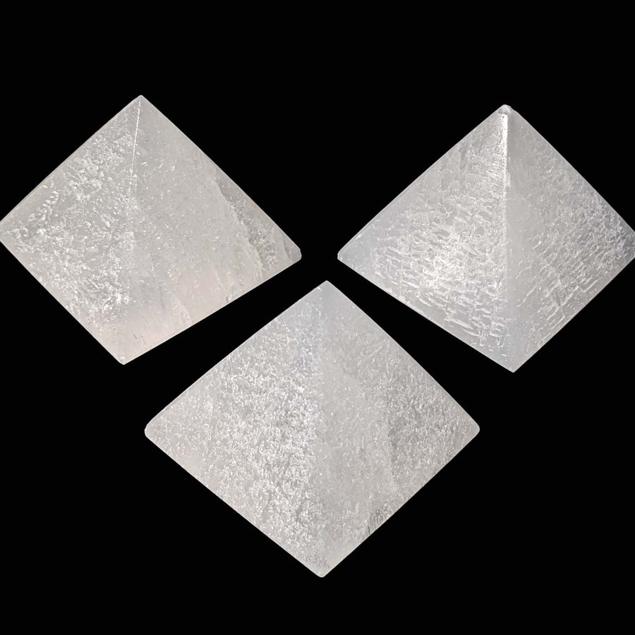 Three white selenite mini pyramids in a triangular formation for peaceful energy