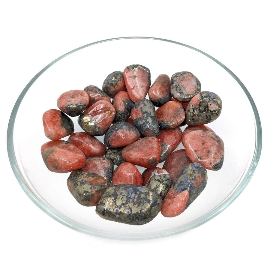 Polished pink and black Rhodonite stones in a glass bowl with referral history benefits