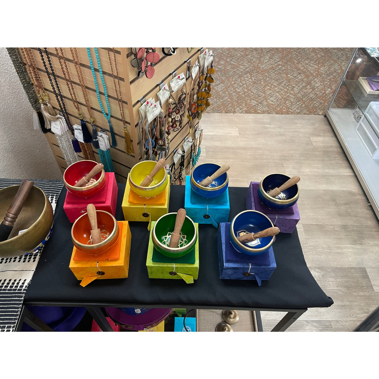 Colorful vintage coffee grinders in rainbow order near a Chakra Singing Bowl Box Set