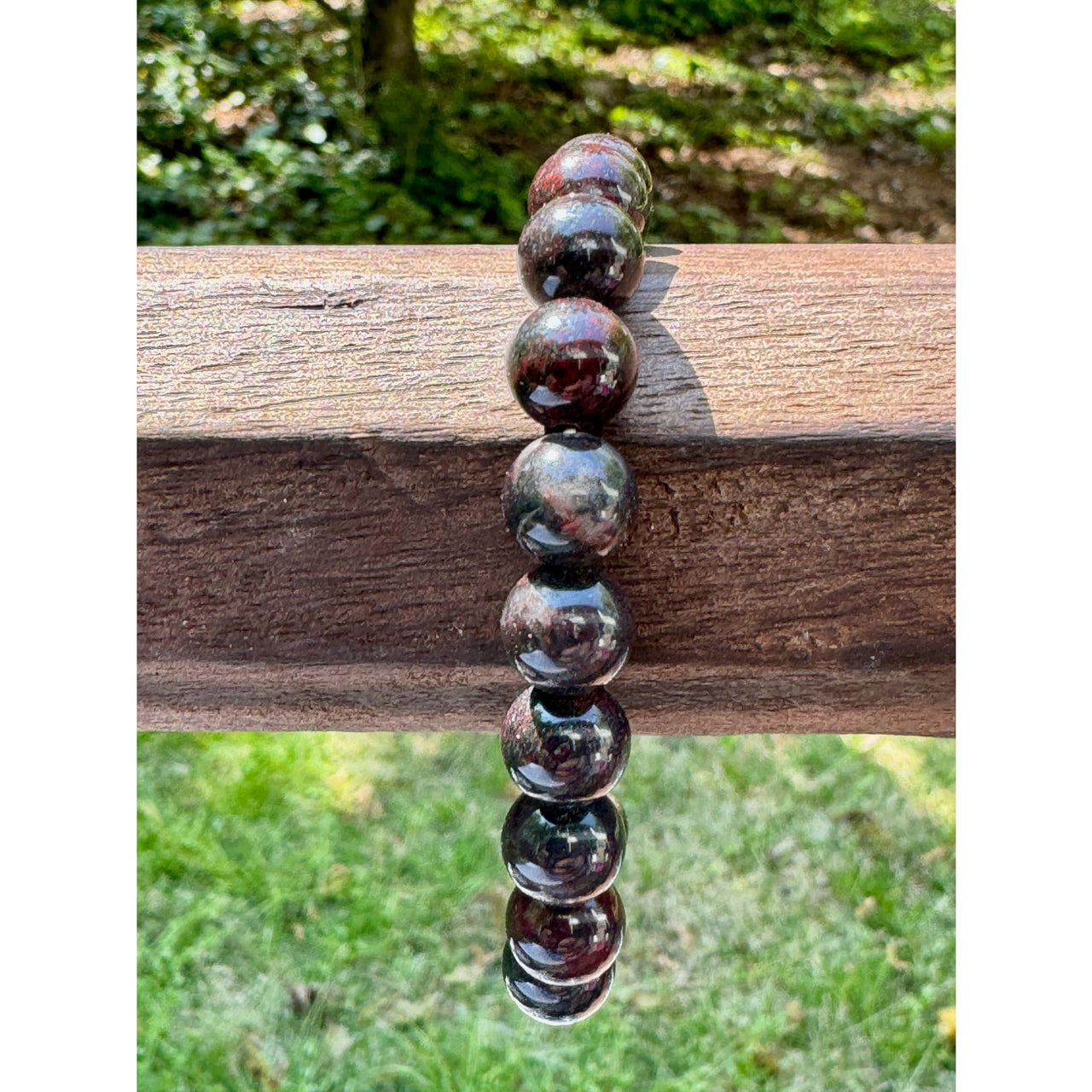A polished 8 mm bloodstone bracelet with dark red and black banded garnet beads and a smooth glossy finish