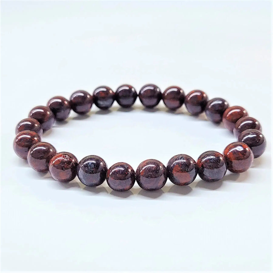 An 8 mm bloodstone bracelet featuring polished deep red garnet beads with subtle golden streaks and a smooth rounded design