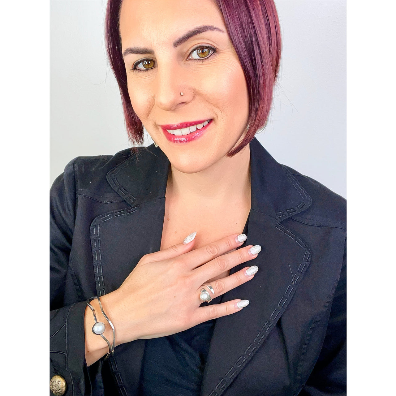 A woman with pink hair wearing a black jacket and Balaam Jewelry sterling silver freshwater pearl ring