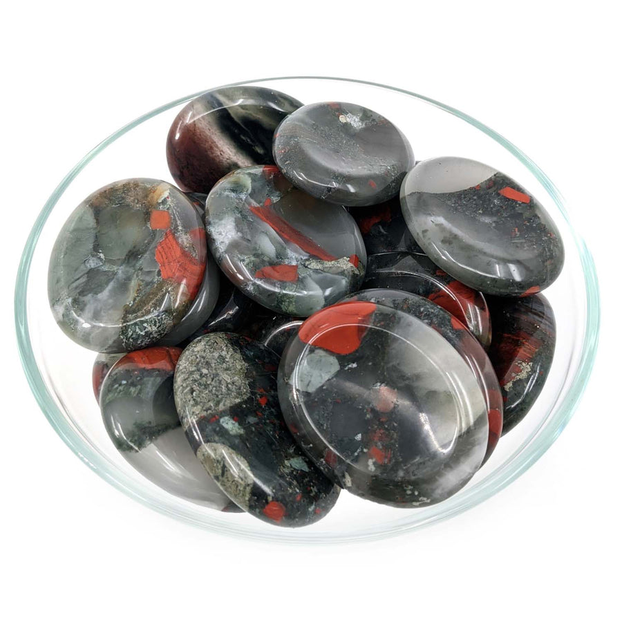 Polished black and red African Bloodstone Thumb Stone pebbles in a clear glass bowl