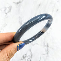 Thumbnail for A hand holding an Agate Round Bangle Crystal Bracelet #LV1969 with blue banded agate