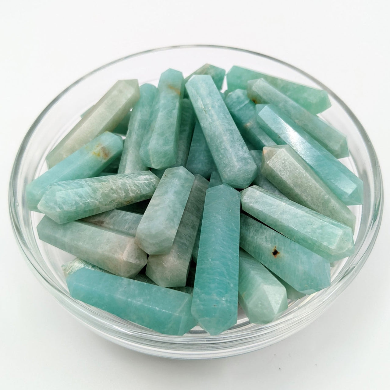 A bowl of green and white quartz chips with Amazonite Mini DT Point Wand in display