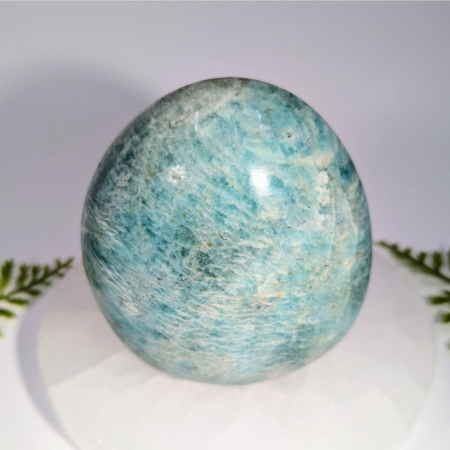 Polished oval-shaped amazonite gemstone with swirling light blue and white veining perfect for jewelry and crystals