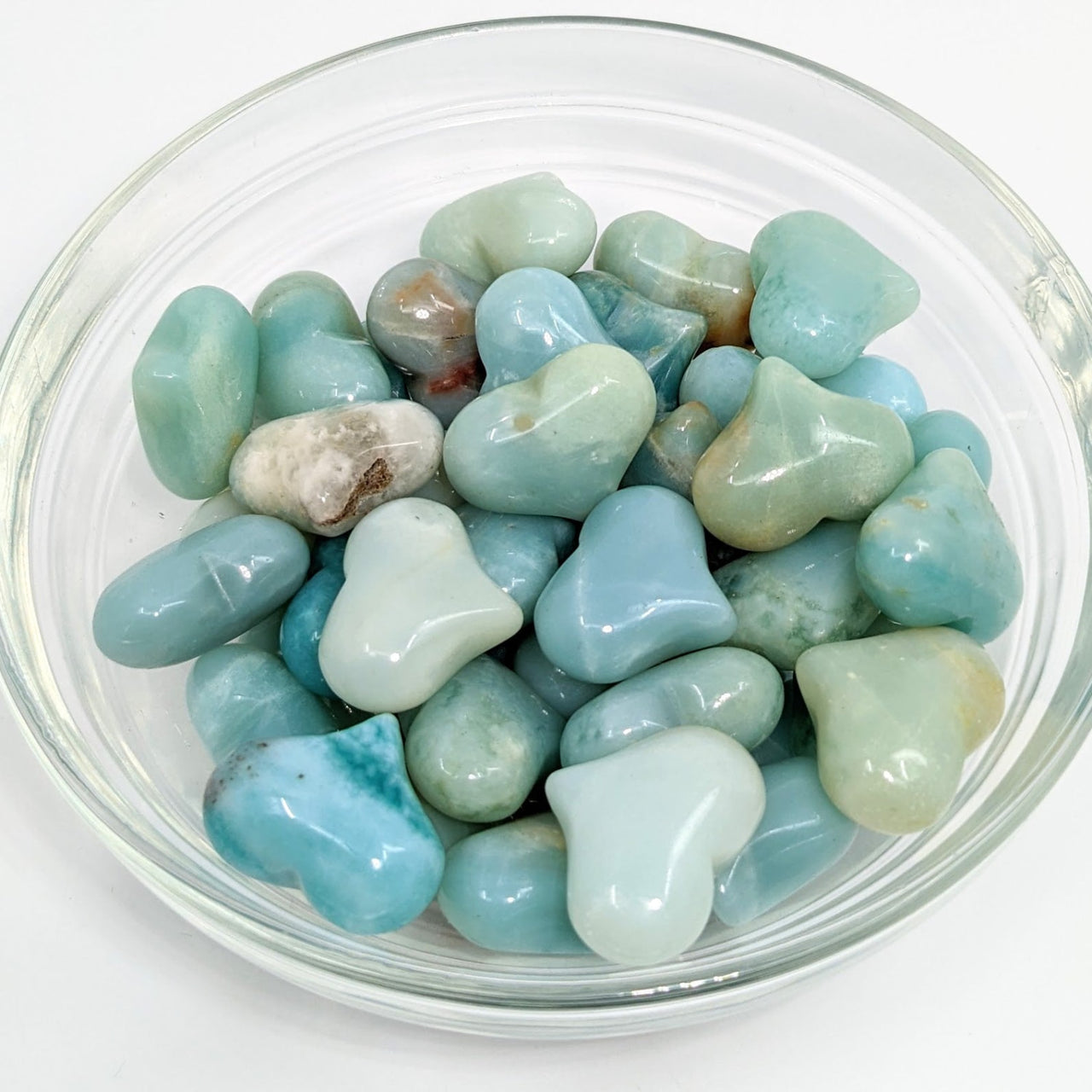 Amazonite .97’ Mini Puffy Heart in a bowl filled with blue and green rocks