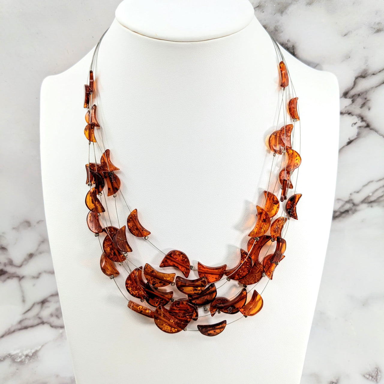 Amber Crescent Moon Floating Wire Necklace accented with orange leaves on a white mannequin