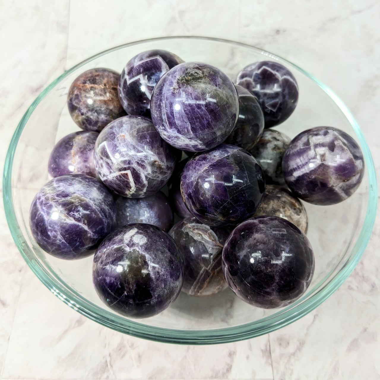 A close-up of a bowl of purple marbled potatoes on a marble counter; Amethyst Sphere #LV2362