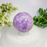 A polished purple amethyst sphere 2.1 inches with natural crystalline patterns on a clear glass stand