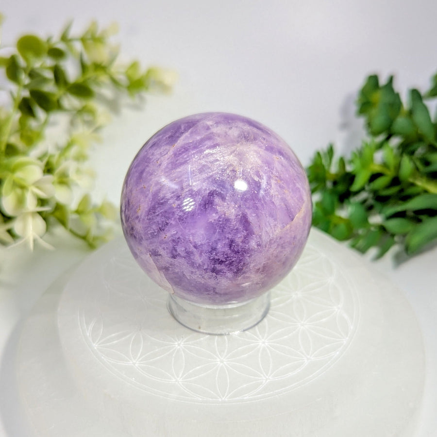 A polished purple amethyst sphere 2.1 inches with natural crystalline patterns on a clear glass stand