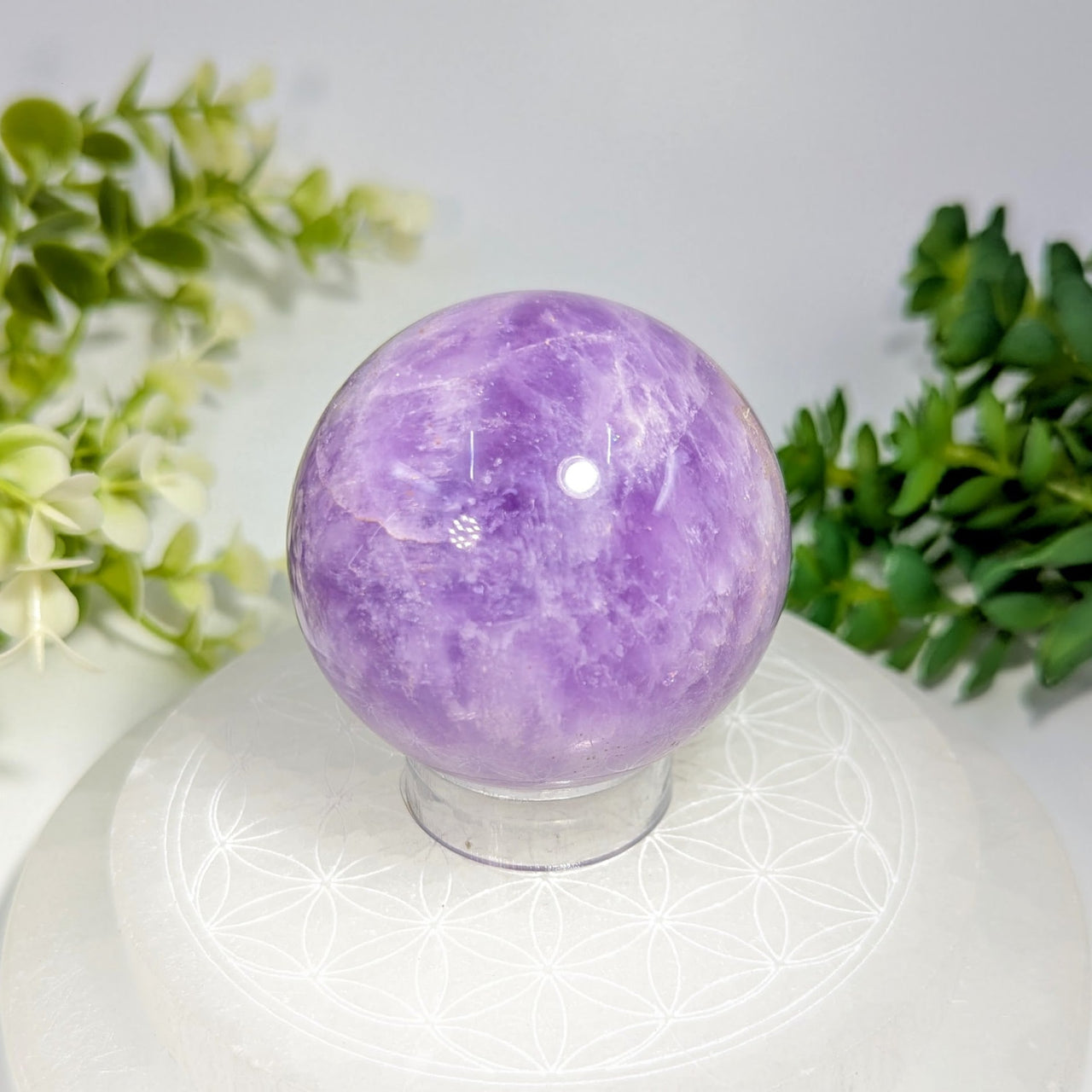 A polished translucent purple amethyst crystal sphere 2.1 inches with swirling patterns and a smooth reflective surface