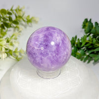 A polished translucent purple amethyst crystal sphere 2.1 inches with swirling patterns and a smooth reflective surface