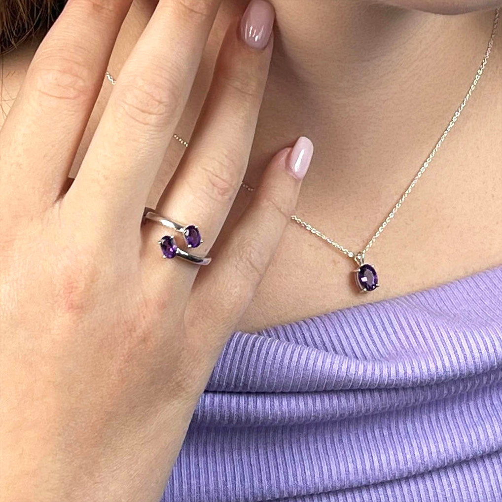 Woman wearing amethyst faceted crystal jewelry set with sterling silver earrings, pendant, ring