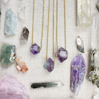 Three delicate gold chain necklaces with faceted amethyst pendants