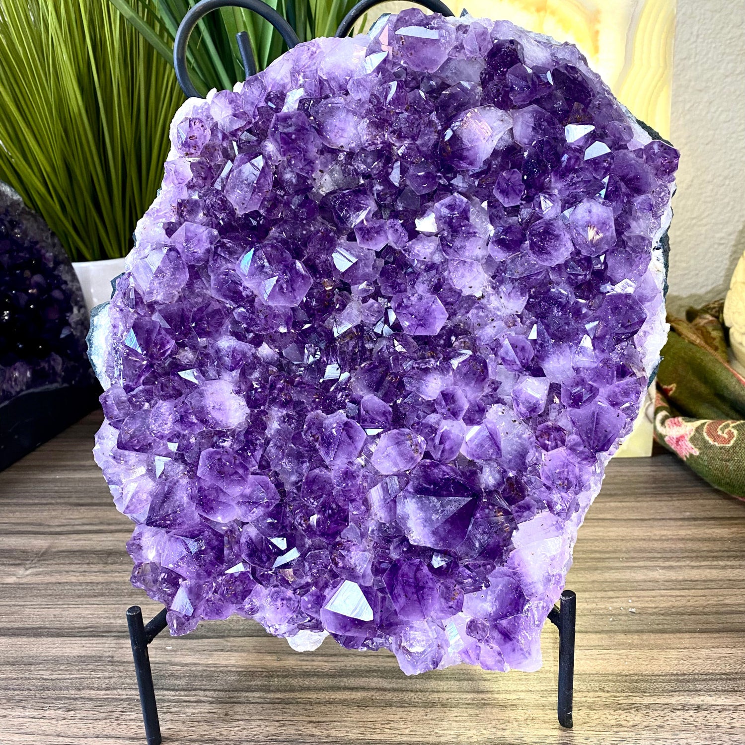 A vibrant purple amethyst geode 9.2 kilo specimen with dense faceted crystals on a black metal stand