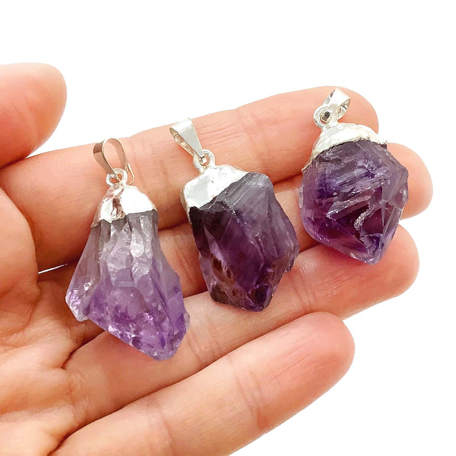Person holding three Amethyst Rough Point Pendants showcasing item tier benefits