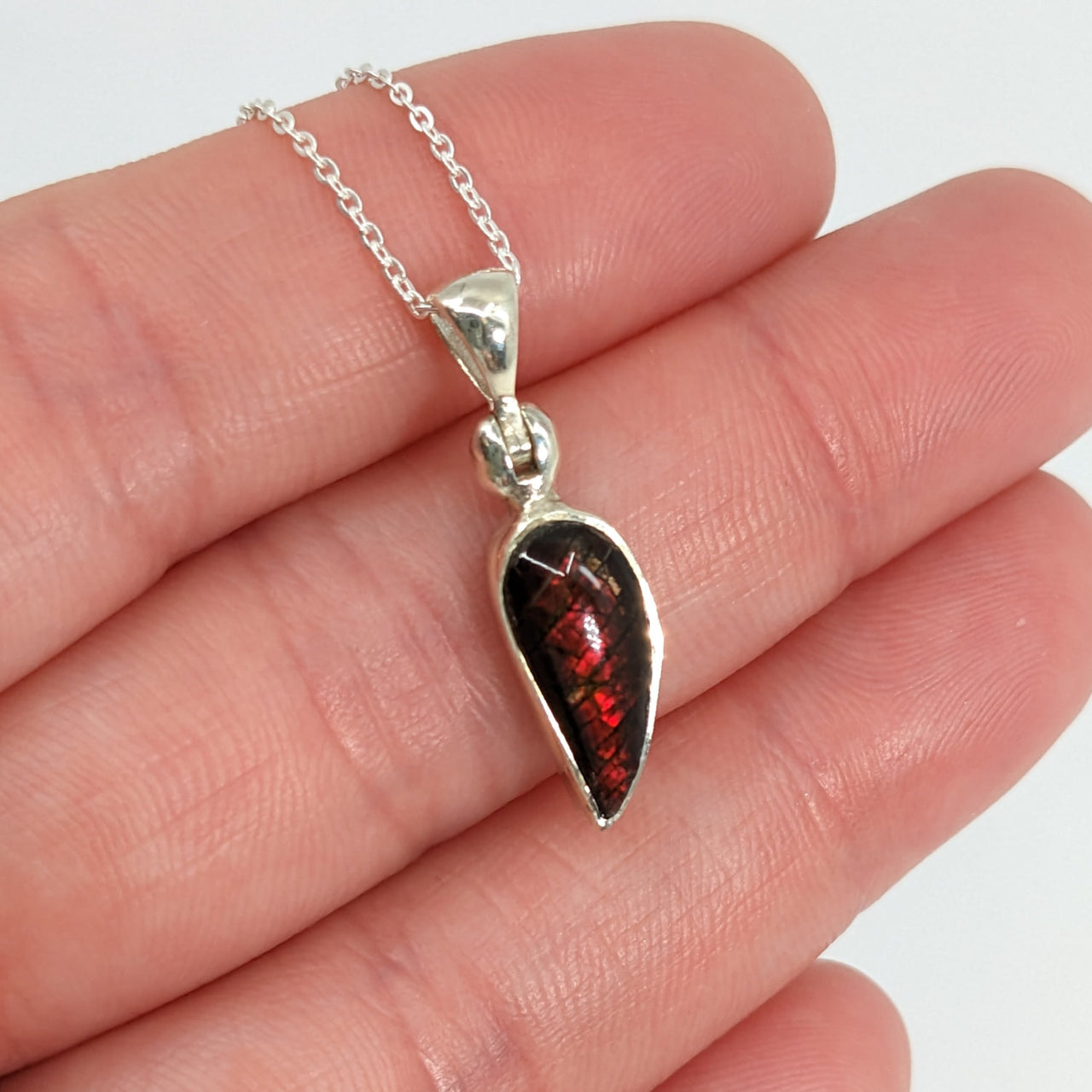 Ammolite 18’ sterling silver pendant #SK8914 held with a red garnet necklace