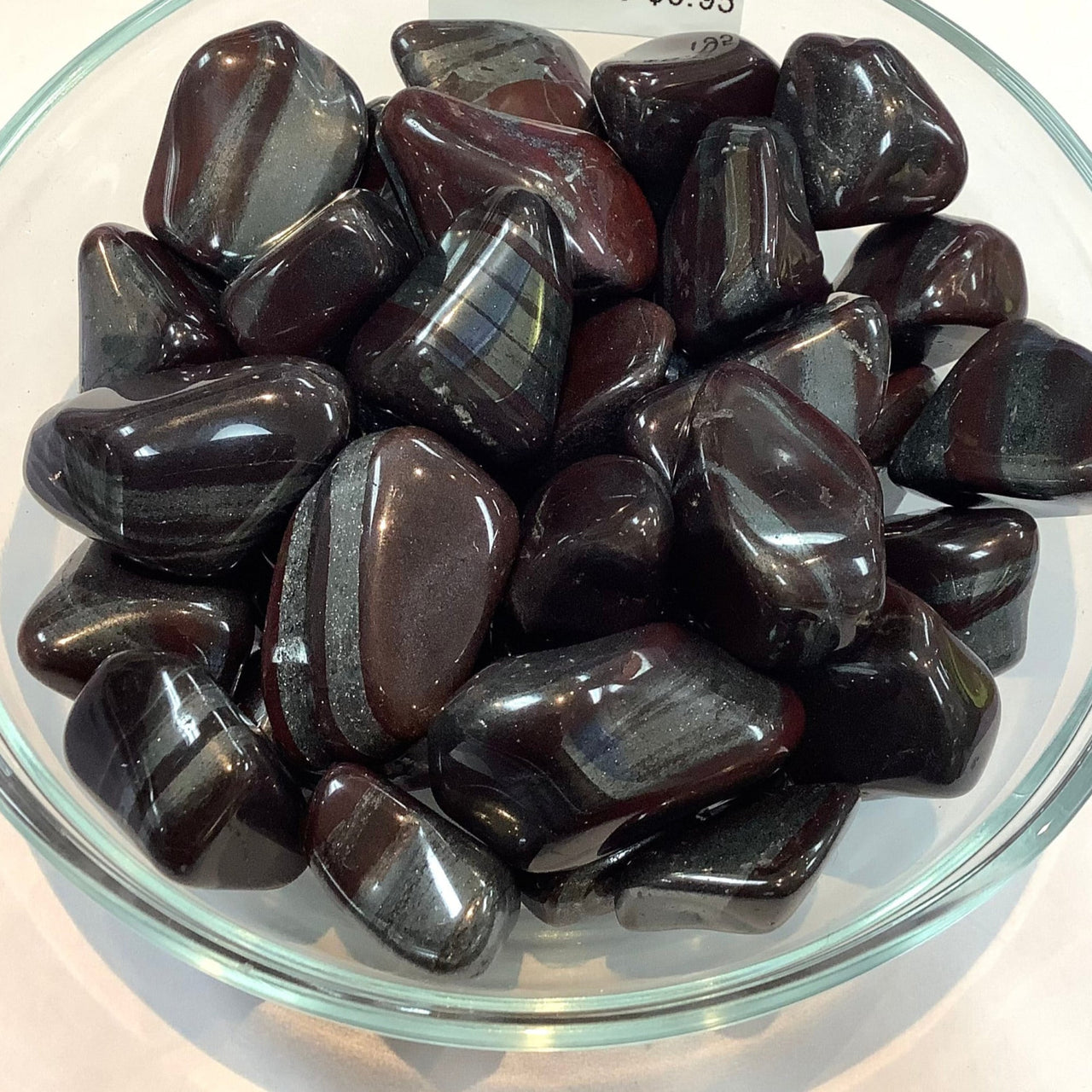 Polished dark red garnet stones in glass bowl for Ancestralite Tumbled collection