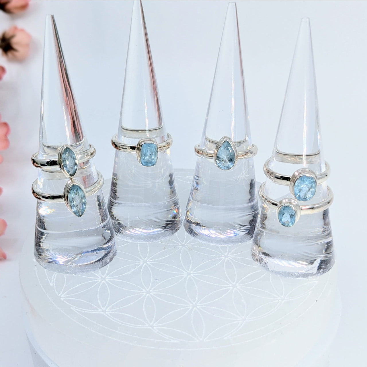 Four glass ring holders showcasing silver-toned Aquamarine Faceted Rings with blue gemstones