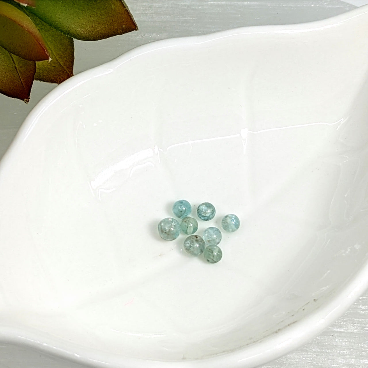 Light blue-green Aquamarine 3mm mini round beads clustered together in a stylish display