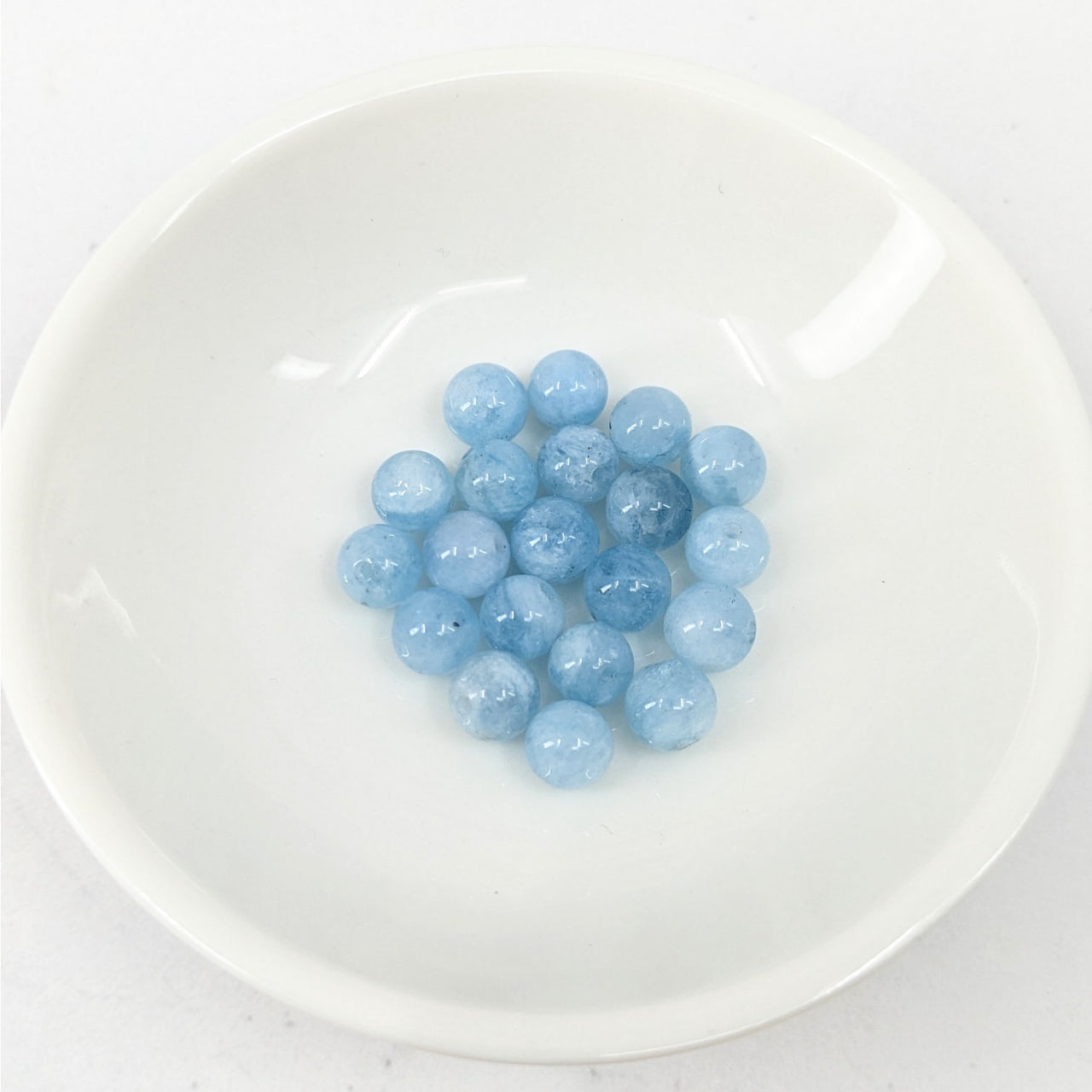 White bowl filled with blueberries, displayed in Aquamarine 6 mm Round Bead 12 pack #LV3636