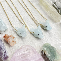 Delicate gold chain necklace with light blue jade wolf pendant and black bead eyes
