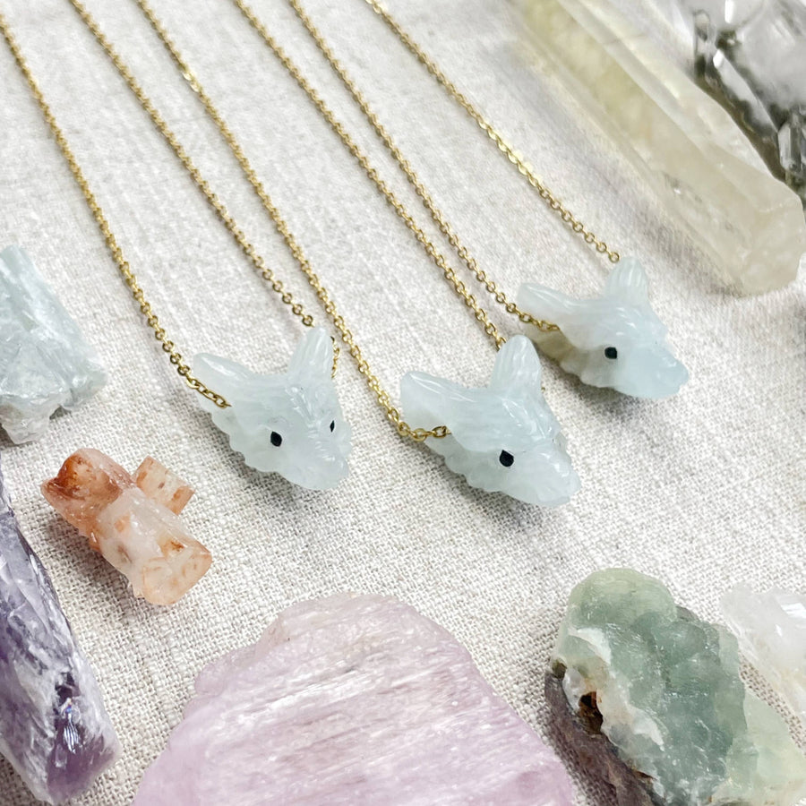 Delicate gold chain necklace with light blue jade wolf pendant and black bead eyes