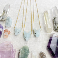 Three delicate gold chain necklaces with light blue jade fox pendants and black bead eyes