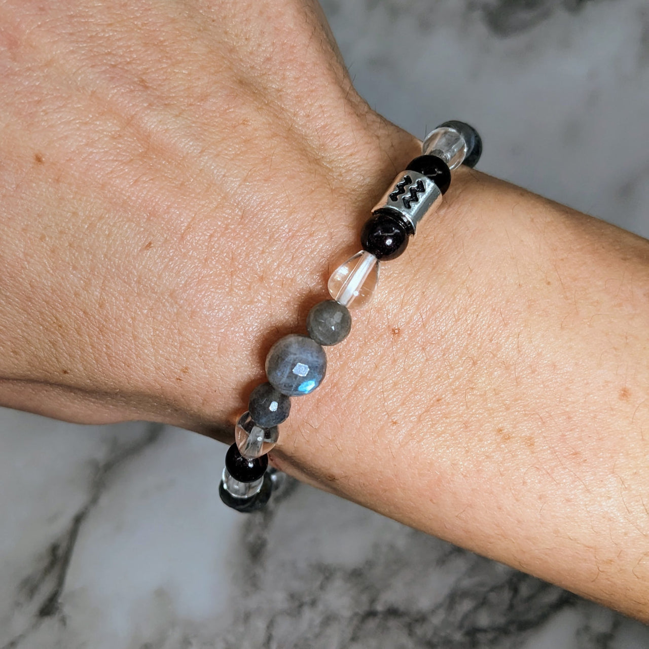 Aquarius Zodiac Handmade Beaded Bracelet with black and white stone on man’s wrist #LV2890