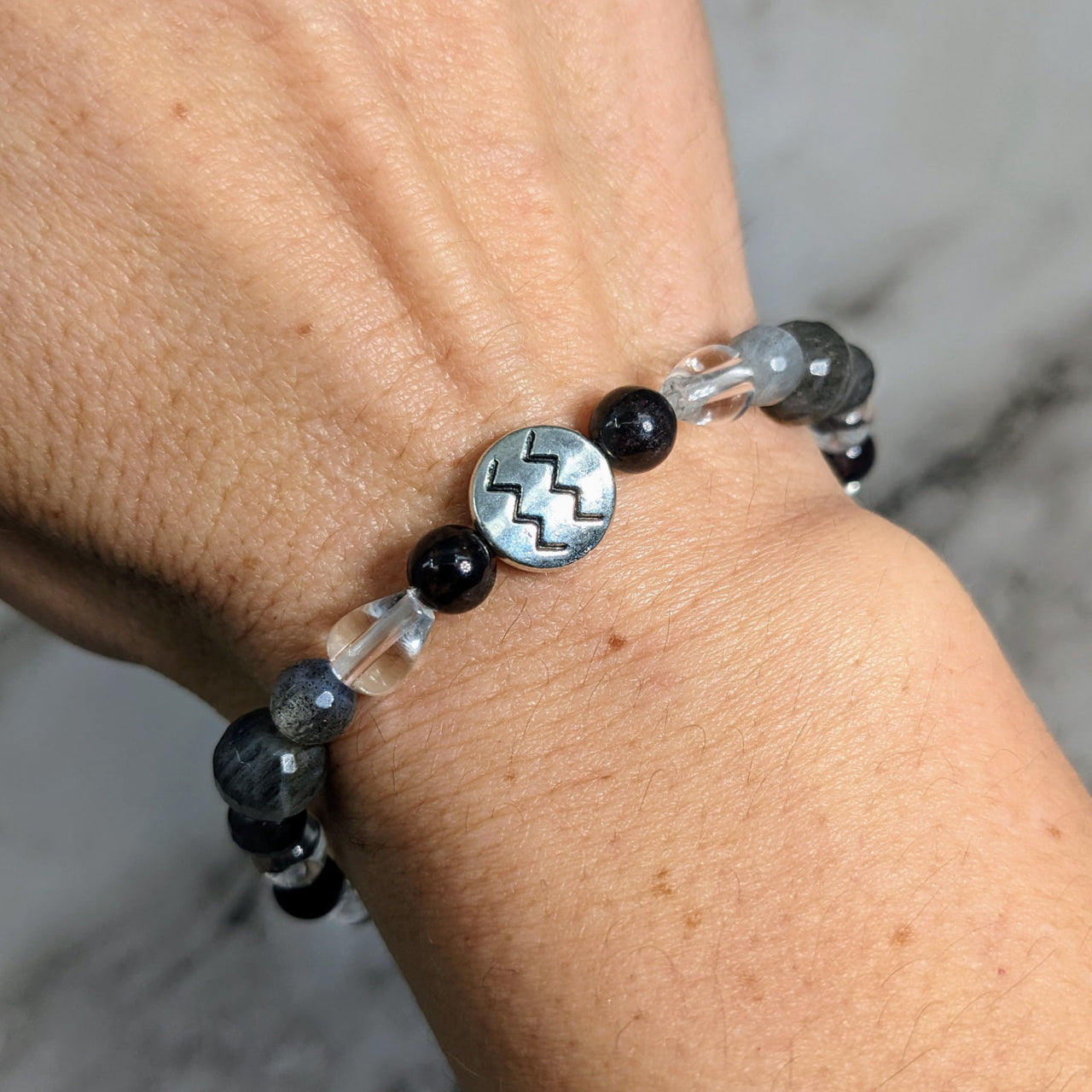 Woman’s hand wearing ’Aquarius Zodiac Handmade Beaded Bracelet’ with black and white glass beads