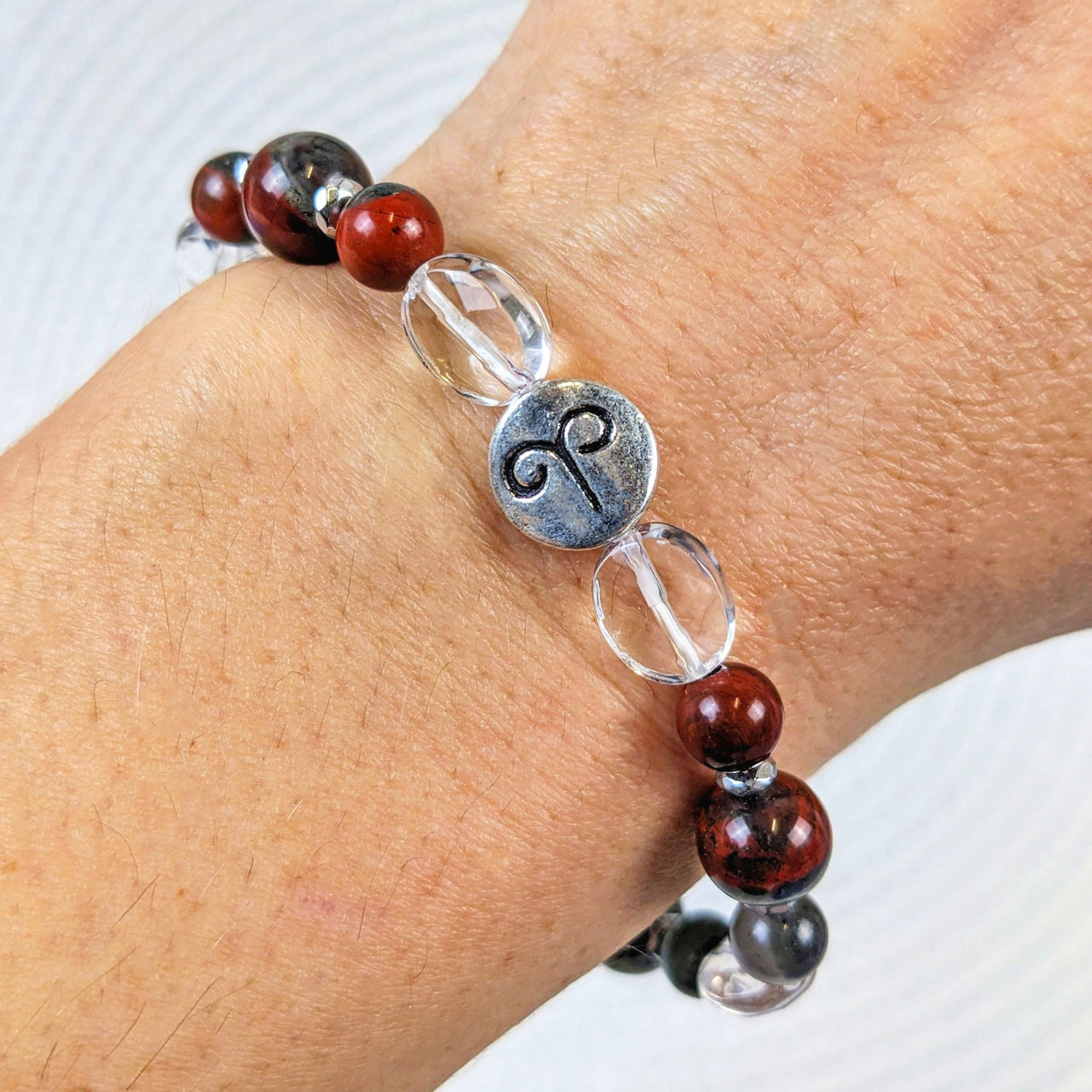 Woman’s hand wearing Aries Zodiac Handmade Beaded Bracelet with red and black glass beads