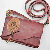 Maroon leather crossbody pouch with tan ammonite fossil applique and braided tie