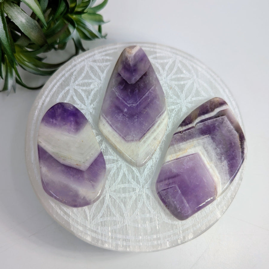 Three chevron amethyst stones from Banded Amethyst Polished Slice showcasing a protective light shield