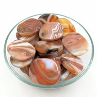 Thumbnail for Textured glass bowl of assorted palm stones on a white surface #SK8961 Banded Carnelian