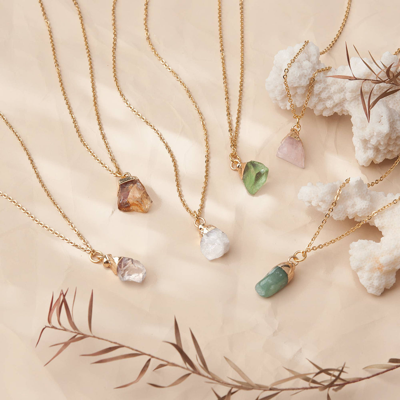 Delicate gold chain birthstone necklaces with raw crystal pendants in earthy tones