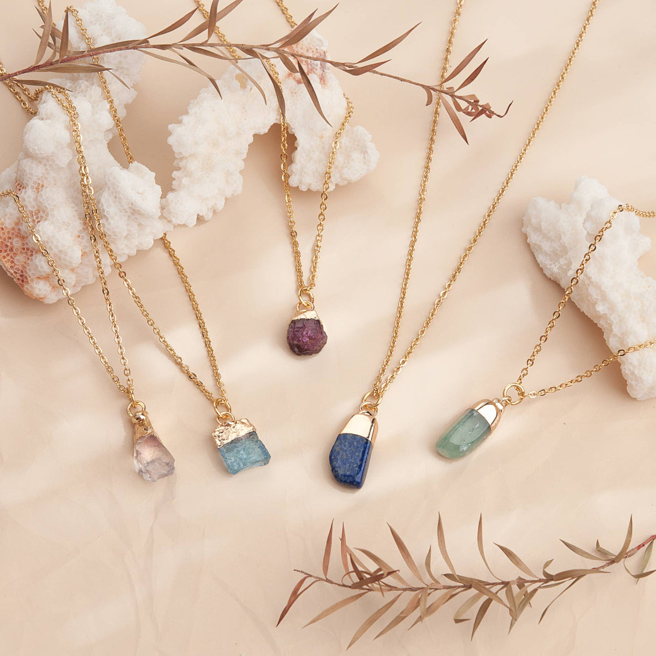 Five delicate gold chain birthstone necklaces with raw purple, blue, green gems
