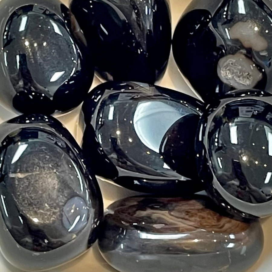 Polished black obsidian stones from Black Agate Tumbled Bliss Crystals showcasing banding types