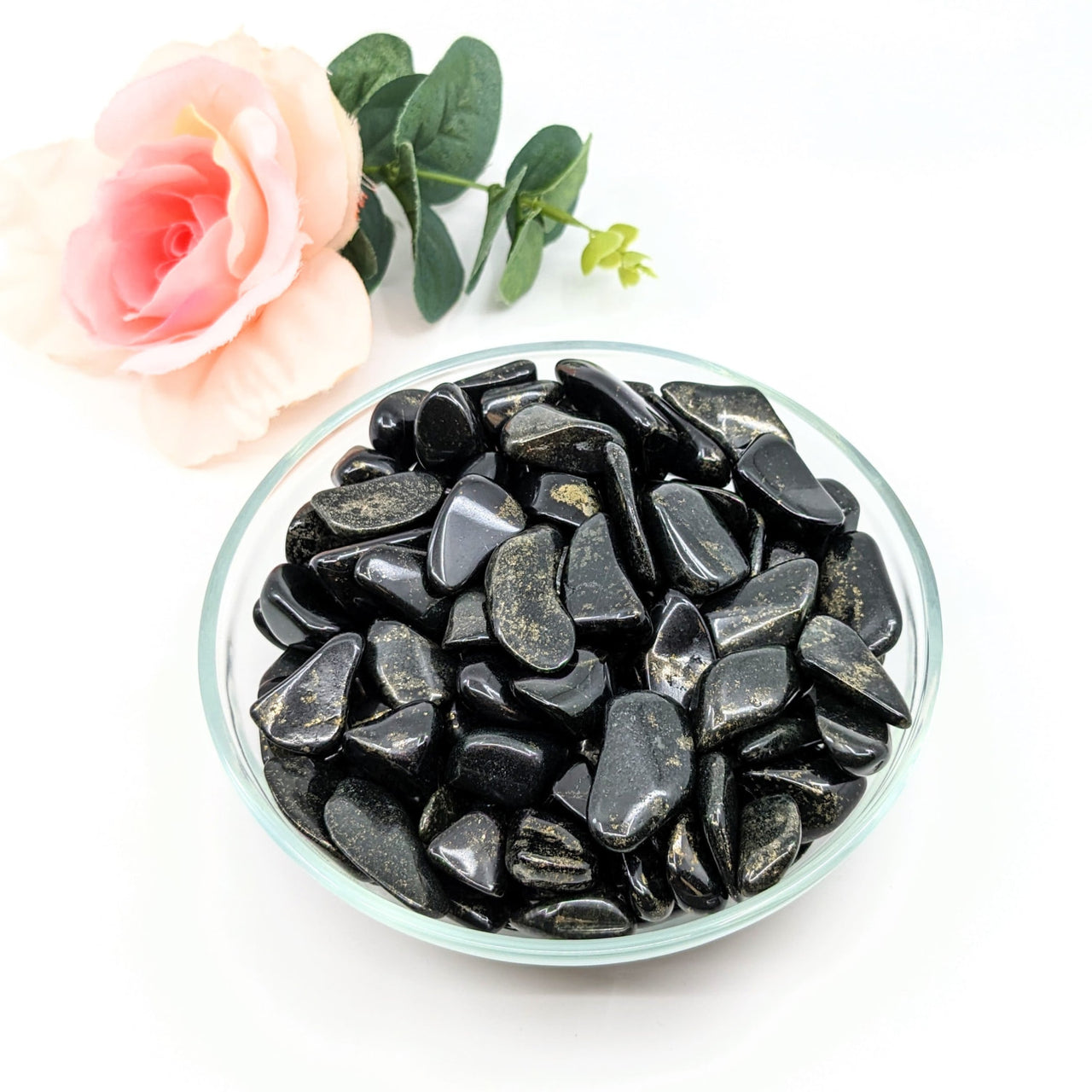 Black Lemurian Jade tumbled stones in a bowl with a rose, perfect for crystal healing