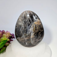 Polished Black Moonstone 4-inch freeform crystal egg with white veining on white base