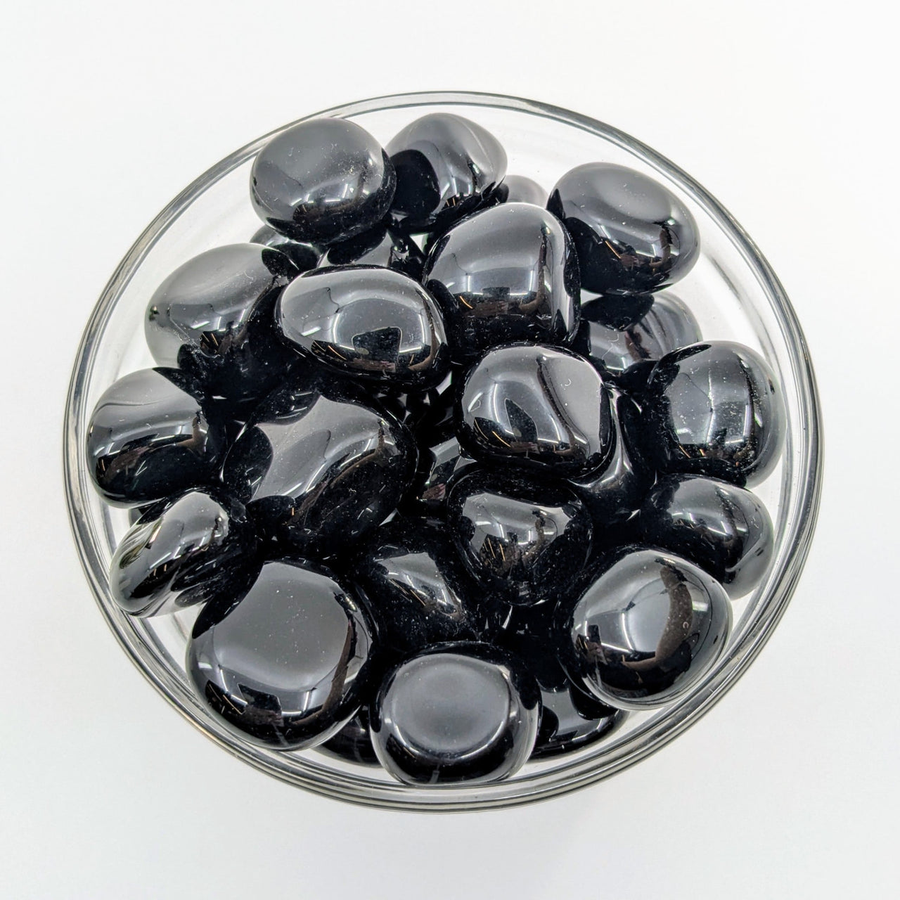 Black olives in a clear glass bowl next to Black Obsidian Tumbled #T419 display