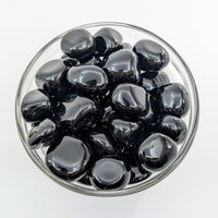 Thumbnail for Black olives in a clear glass bowl next to Black Obsidian Tumbled #T419 display