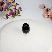 Black obsidian yoni egg with hole on clear acrylic stand