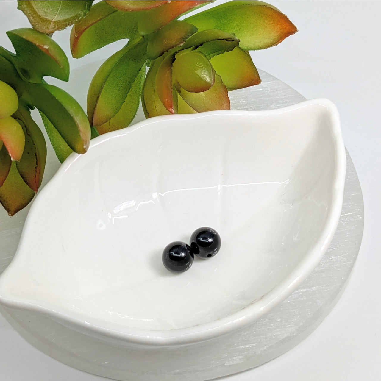 White ceramic bowl with black tourmaline 8.5mm round beads displayed elegantly