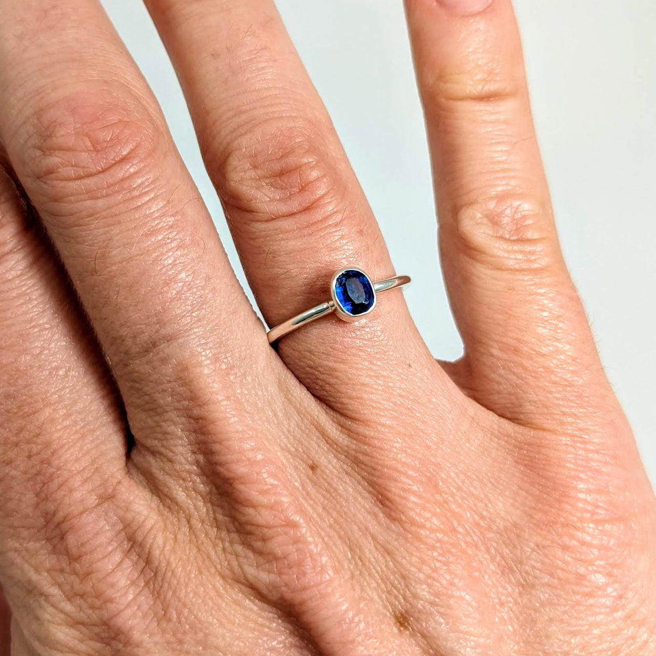 A woman’s hand wearing a sterling silver blue kyanite ring named Blue Kyanite Ring #J510