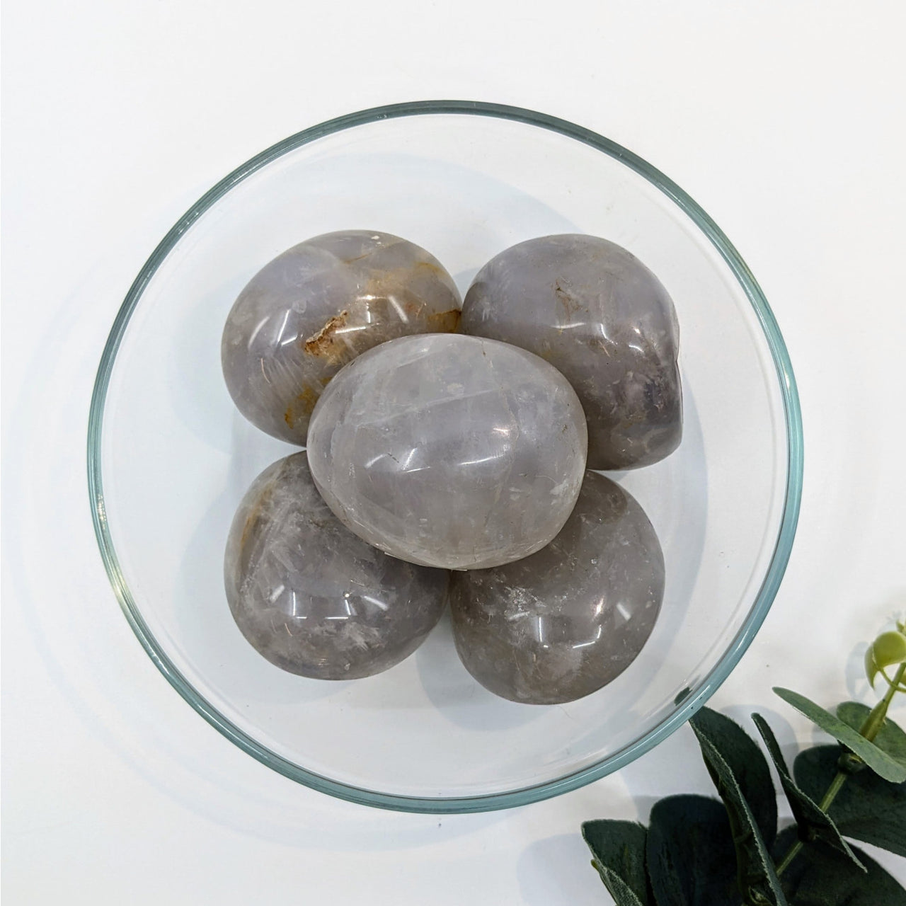 Polished gray quartz stones in a glass bowl featuring Blue Rose Quartz Pebble N068