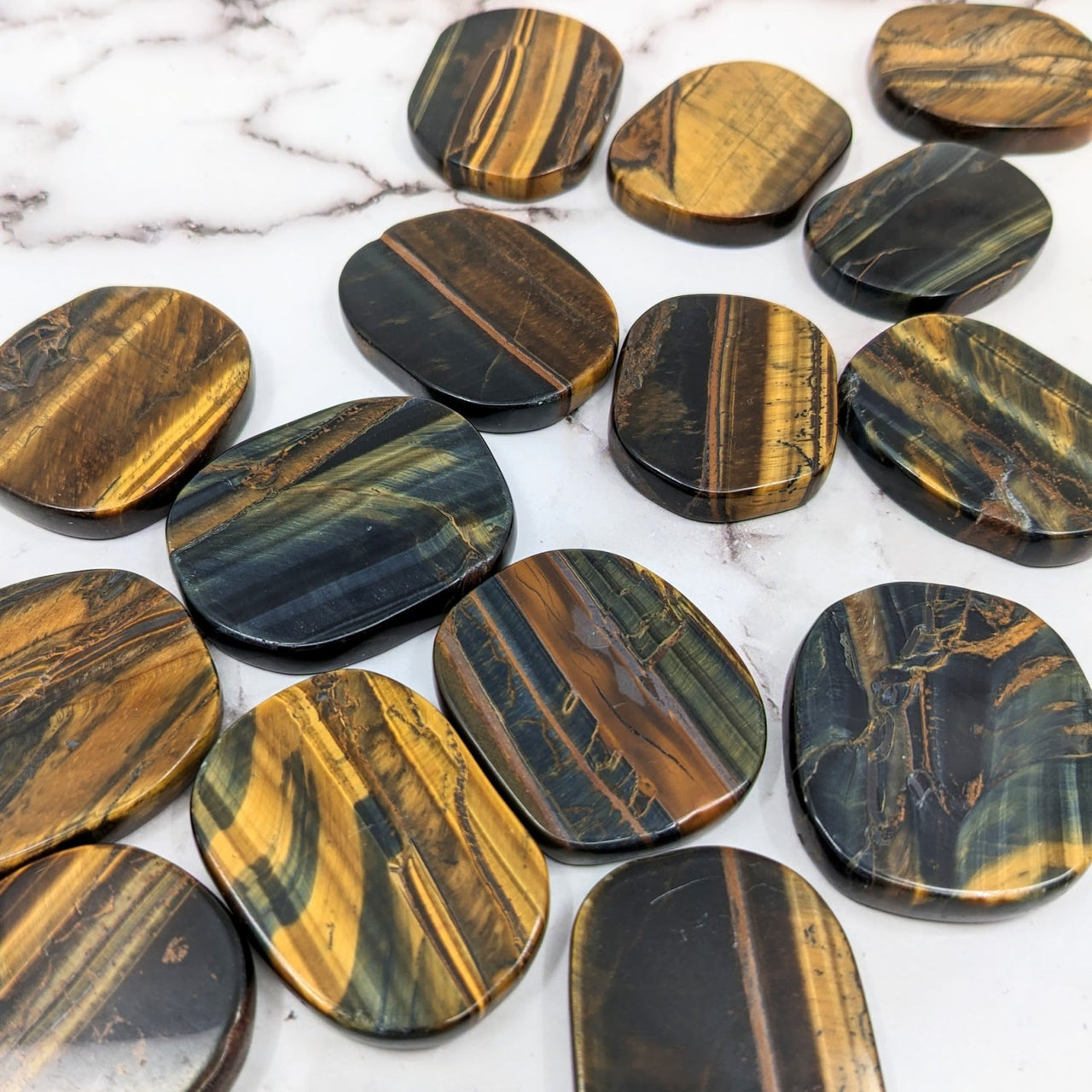 Close up of Blue Tiger’s Eye palm stones on marble surface, product #SK9733